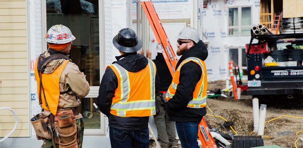 three construction workers standing on jobsite talking.